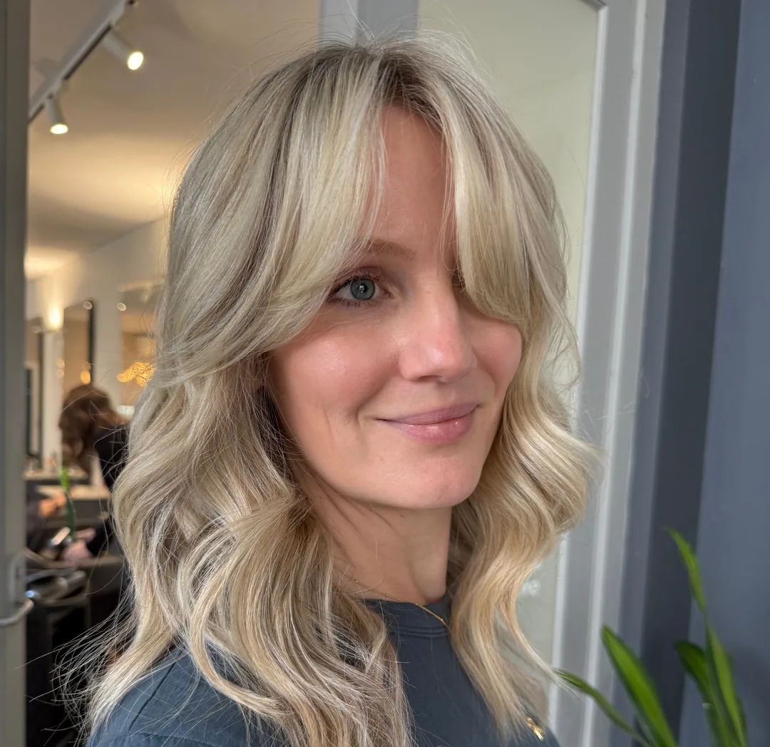 Blonde wavy lob with soft curtain bangs and face-framing layers
