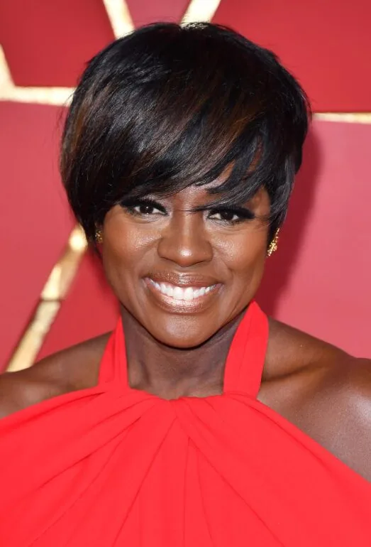 Sleek short pixie with side-swept bangs on a Black woman over 40