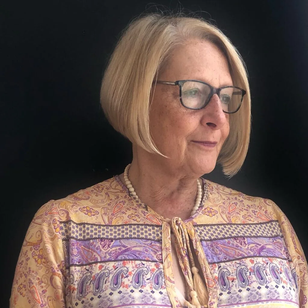 A rounded silver bob with a smooth edge, soft cheekbone shape, and a polished side part. This hairstyle is shown as inspiration for women over 60 with thin hair.