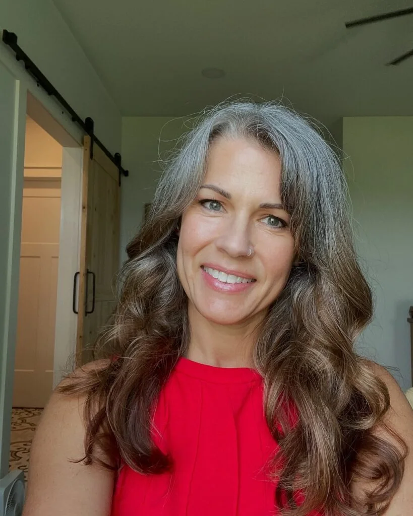 Long silver layers with face-framing movement, soft volume, and a polished gray finish. This hairstyle is shown as inspiration for women over 60 with thin hair.