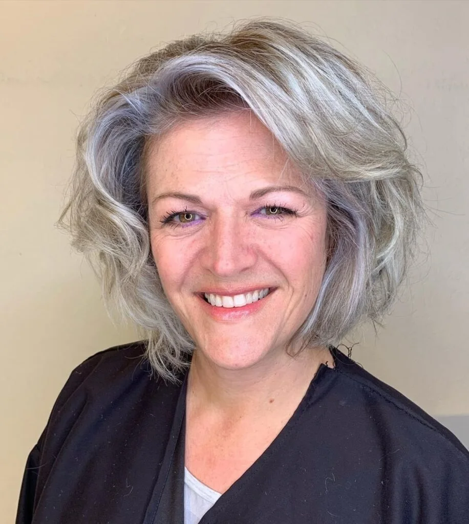 A wavy silver bob with soft texture, light side volume, and a relaxed rounded shape. This hairstyle is shown as inspiration for women over 60 with thin hair.