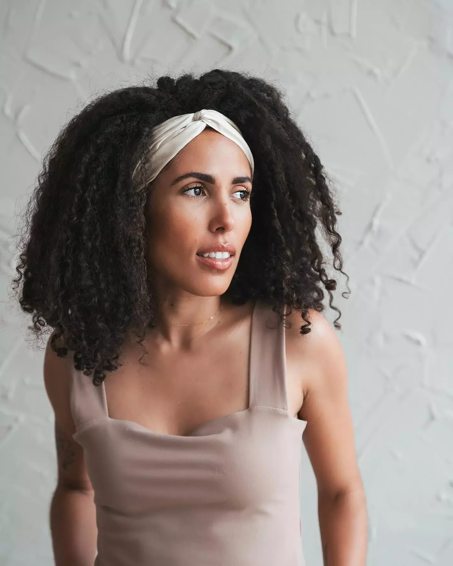 Shoulder length curly hair held back with a white knotted headband