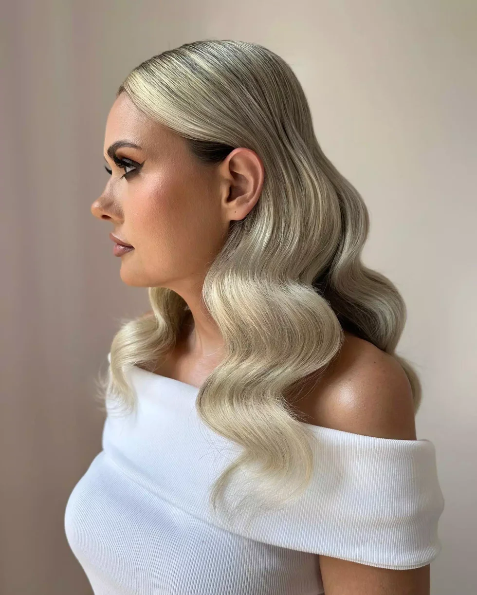 Long blonde old Hollywood waves with a deep side part and smooth S-shaped bends