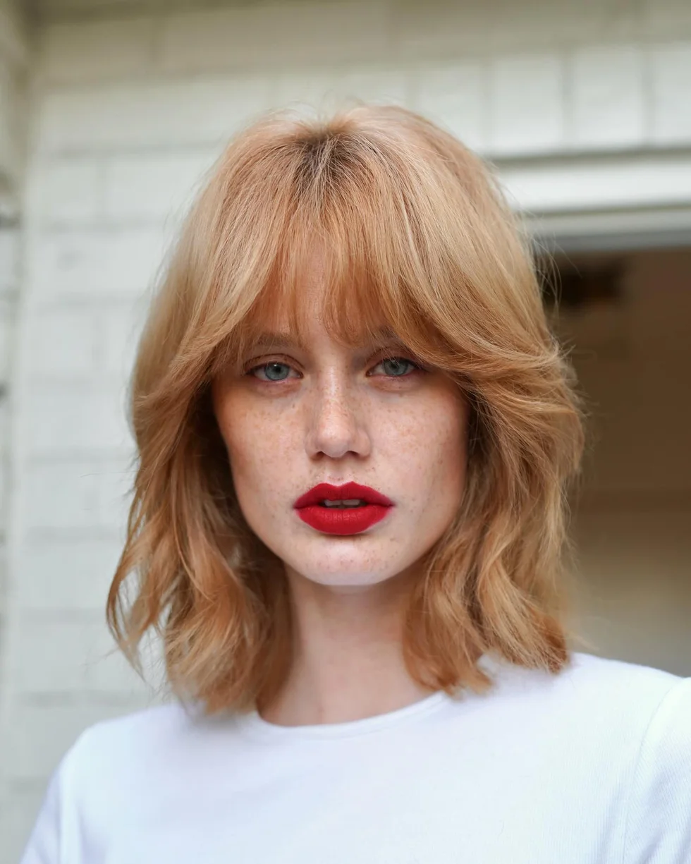 Copper layered bob with soft curtain bangs and textured neck length ends