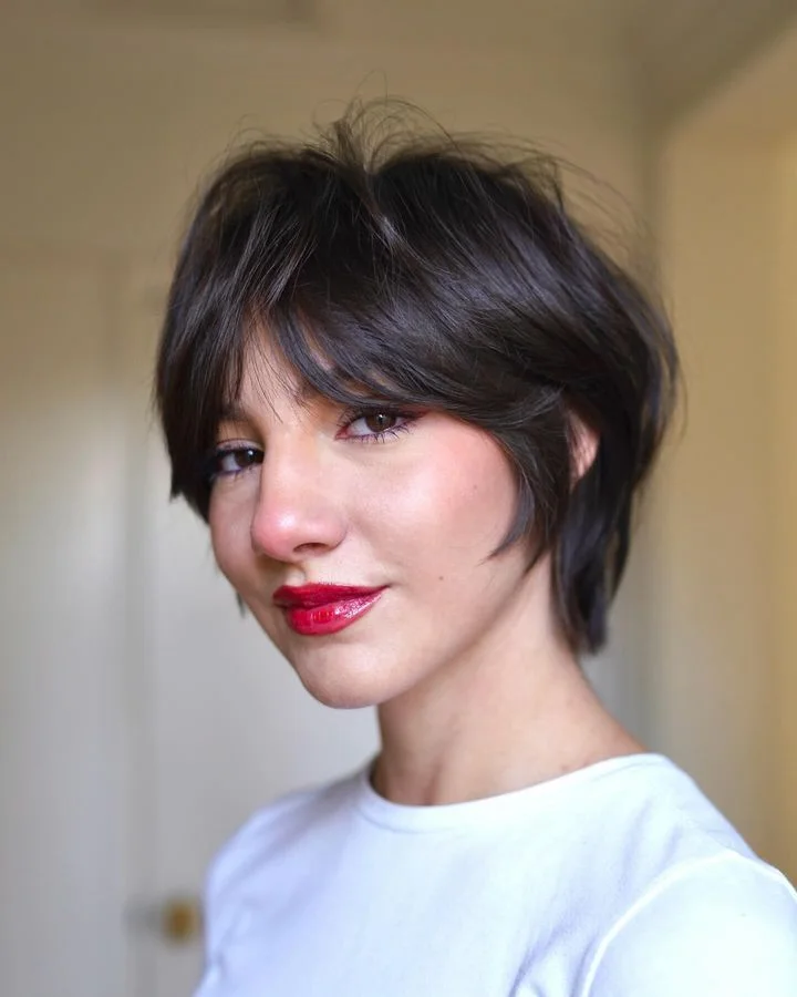 Dark chin-length layered bob with sweeping curtain bangs and soft cheekbone pieces