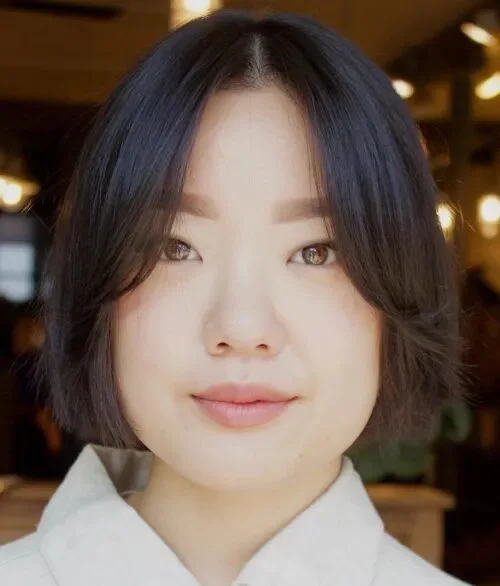 Rounded black chin bob with long curtain bangs and light jaw-length layers