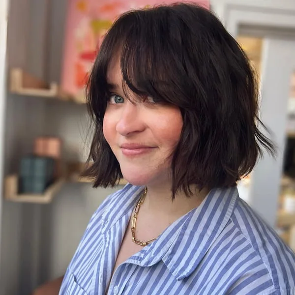 Tousled black neck-length layered bob with curtain fringe and cheekbone movement