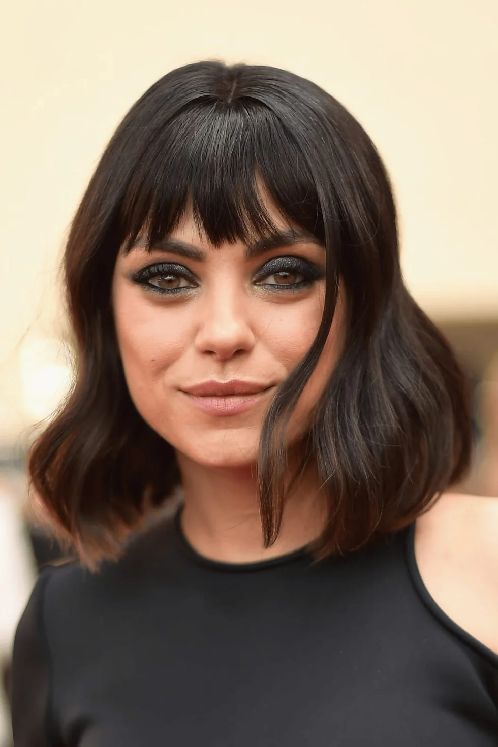 Wavy brunette layered bob with full curtain bangs and soft textured ends