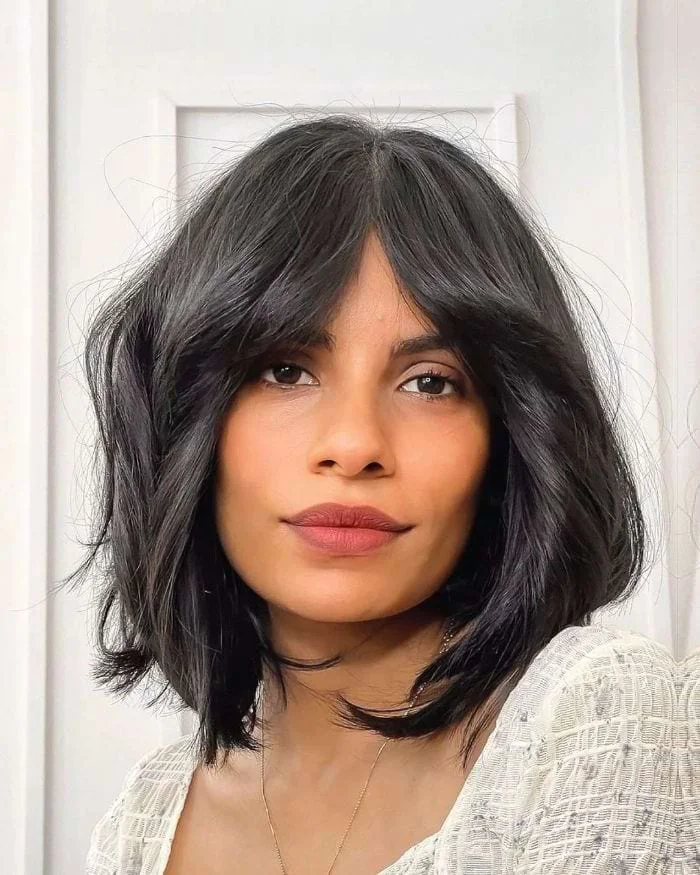 Black textured layered bob with curtain bangs and airy cheekbone pieces