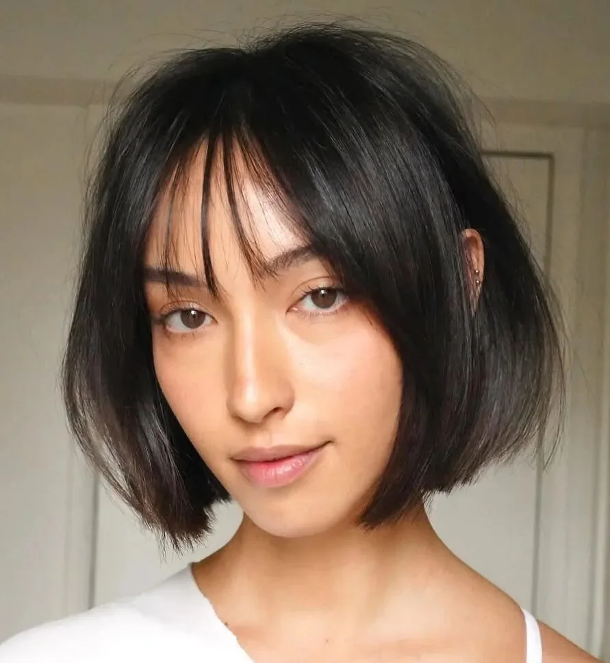 Sleek black bob with light curtain bangs and clean jaw-length shape