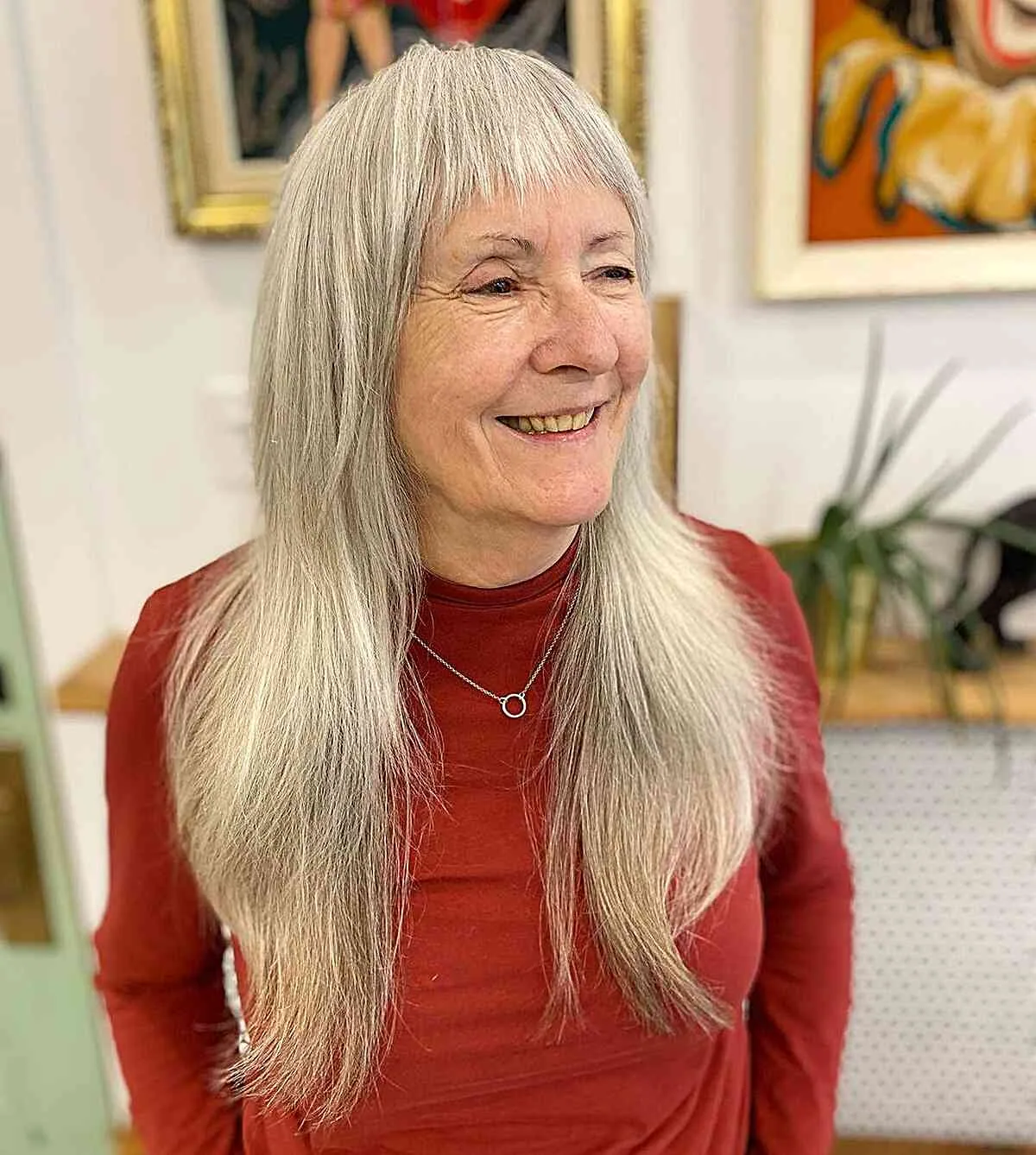 Older woman with long silver layered hair, soft fringe, and straight chest-length movement