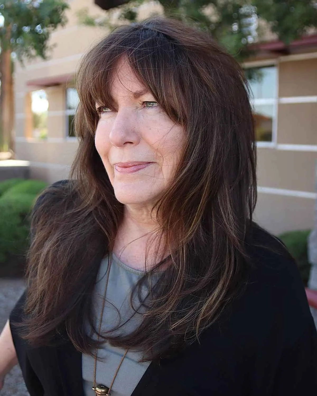 Mature woman with brunette chest-length layers, curtain pieces, and soft wavy movement