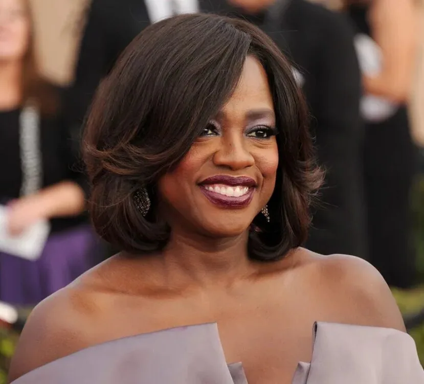Older Black woman with a side-swept layered brunette bob and polished volume