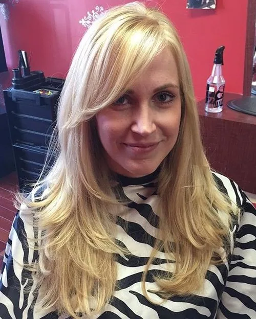 Mature woman with straight blonde long layers and side-swept bangs