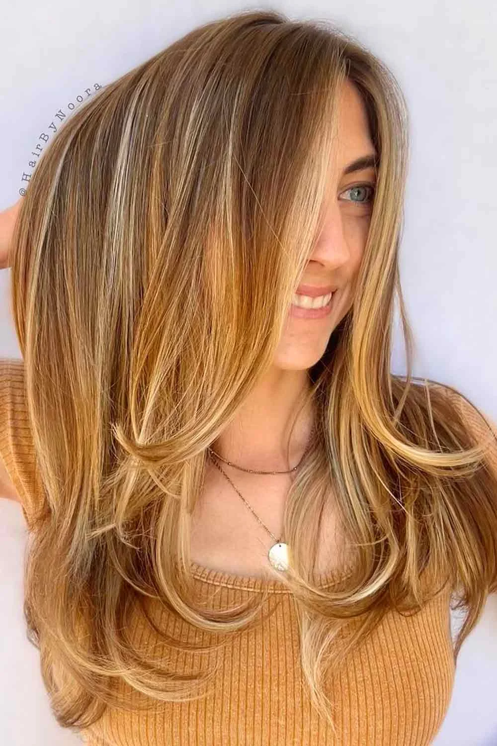 Front view of golden brown hair with long face-framing layers and curved ends