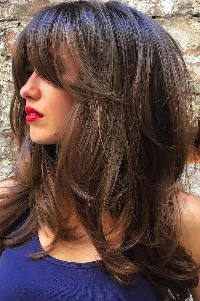 Side view of long brown layers with broad bangs sweeping across the eyes