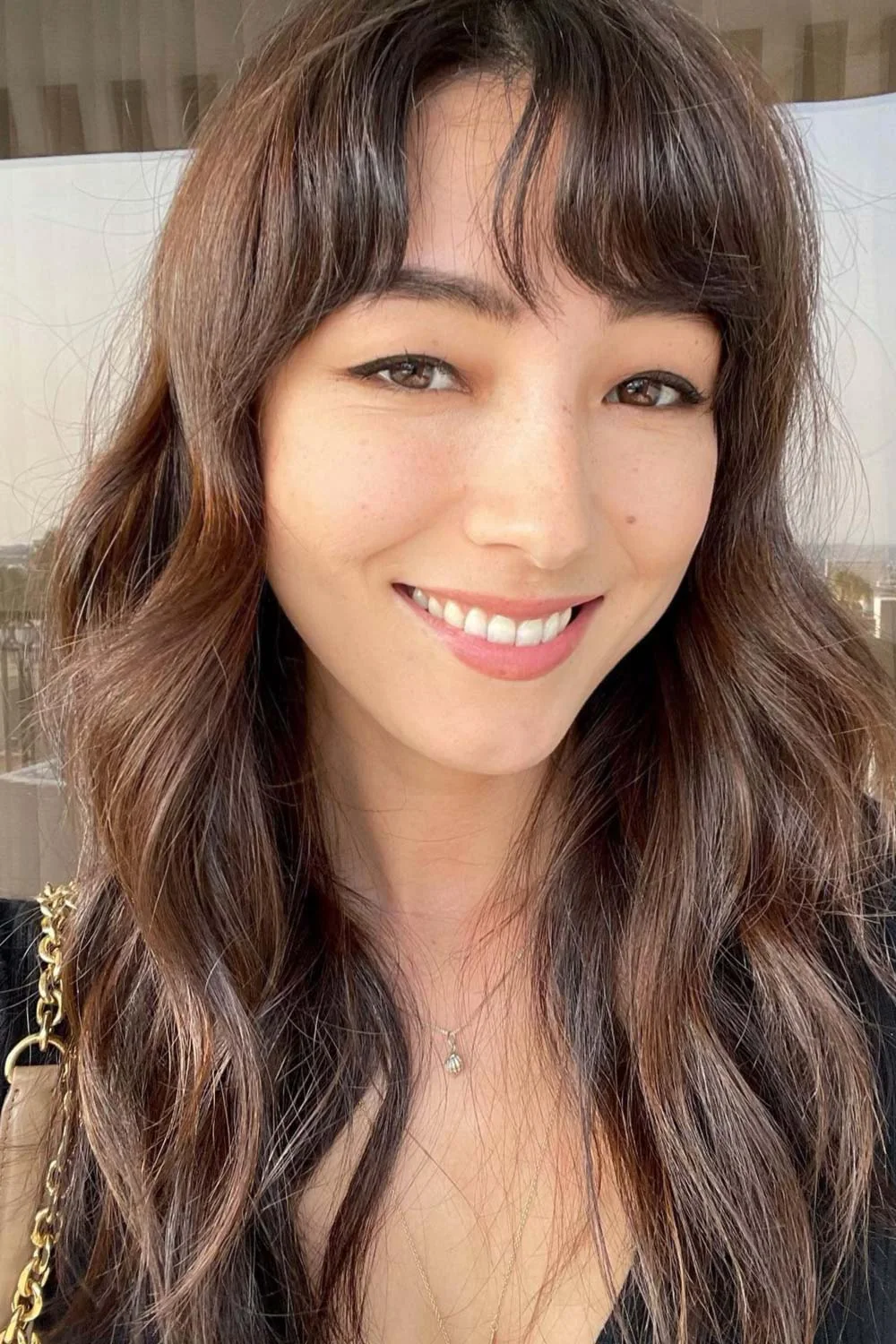 Front view of long brown waves with short parted bangs and fine face-framing strands