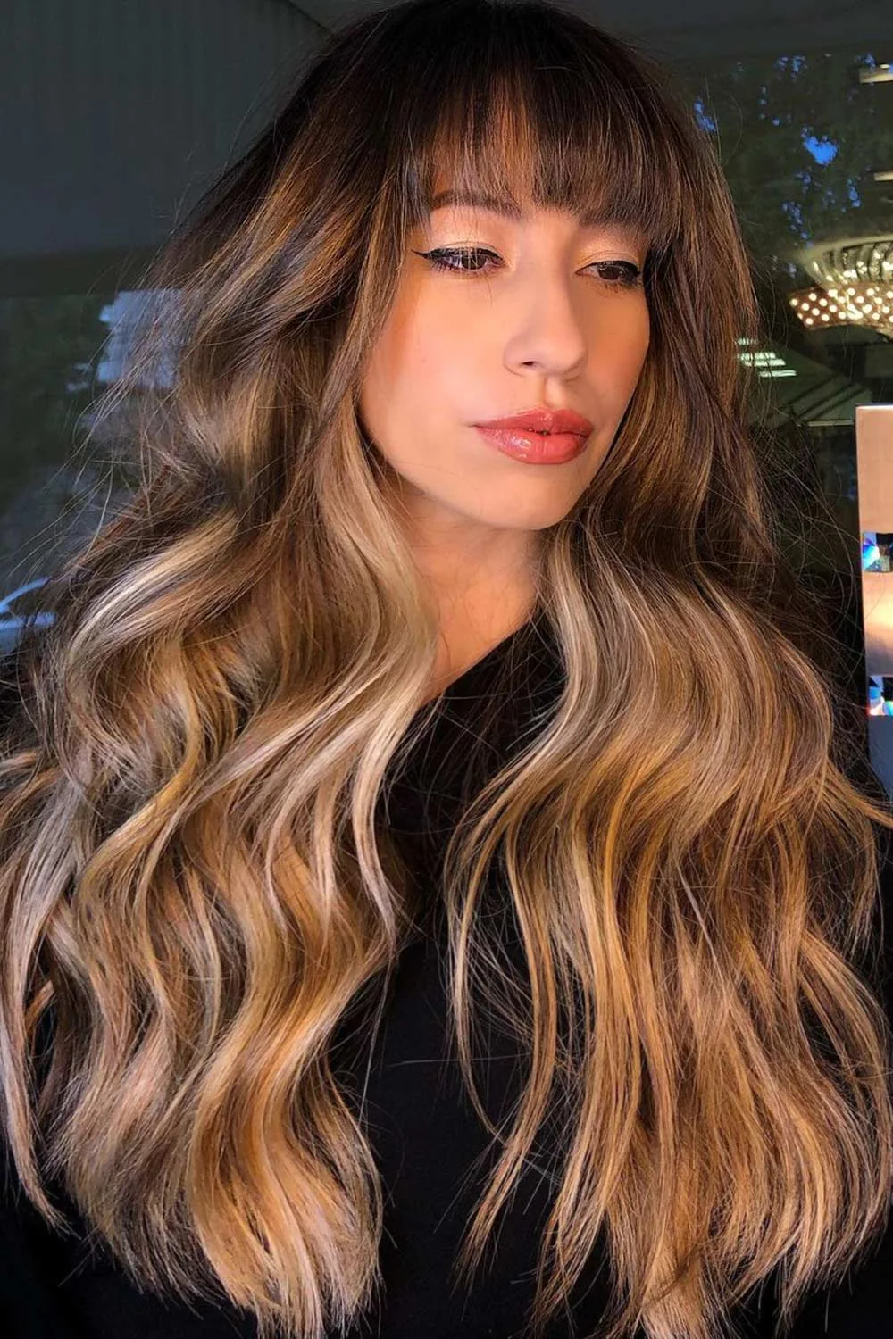 Front-side view of long highlighted brown waves with a fine brow-length fringe