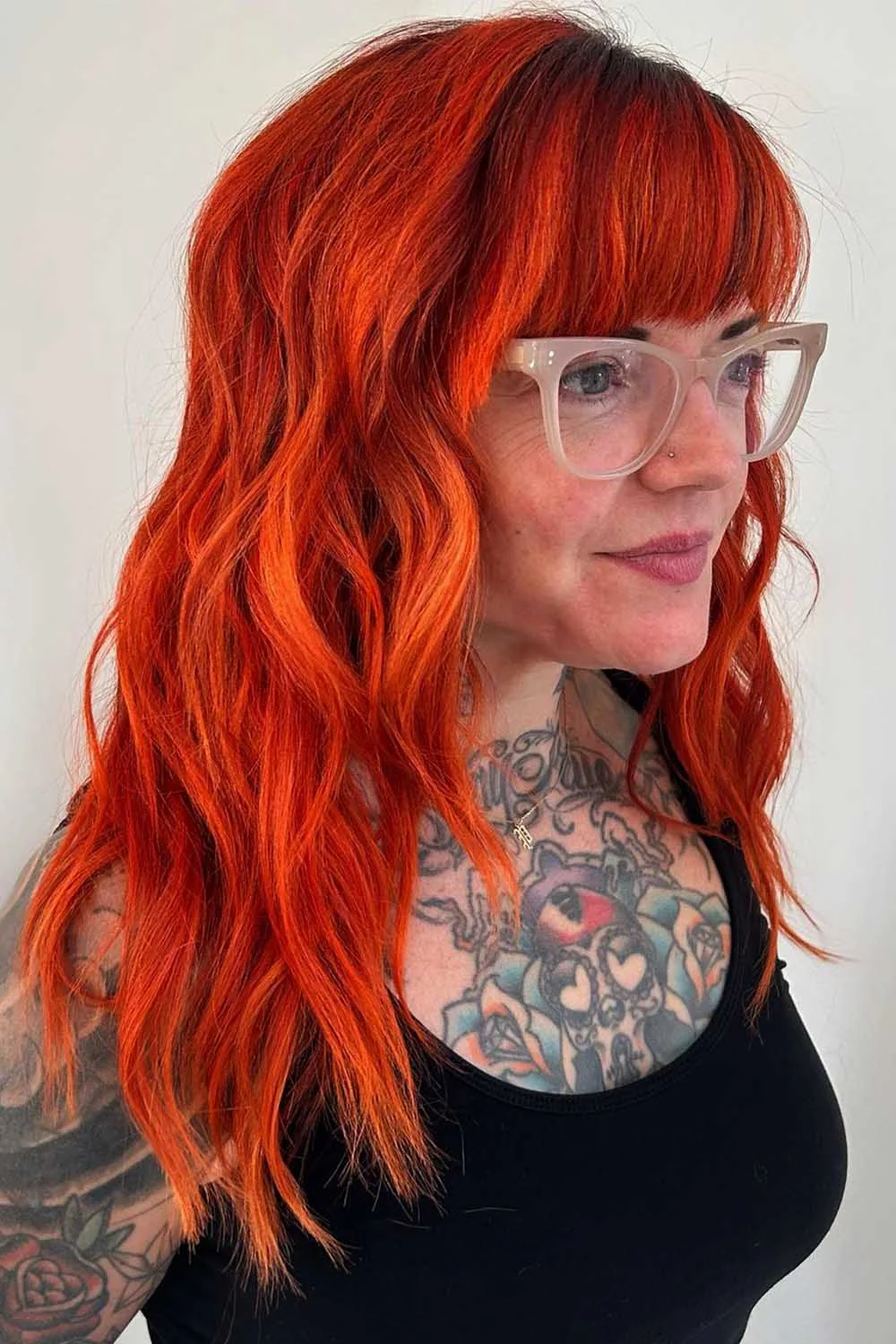 Side-front view of long copper hair with a blunt fringe above glasses
