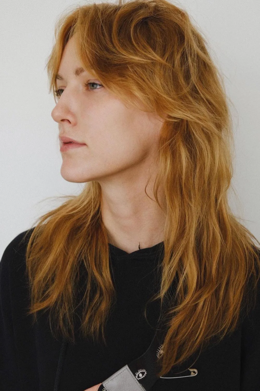 Side-front view of long copper layers with parted sweeping bangs