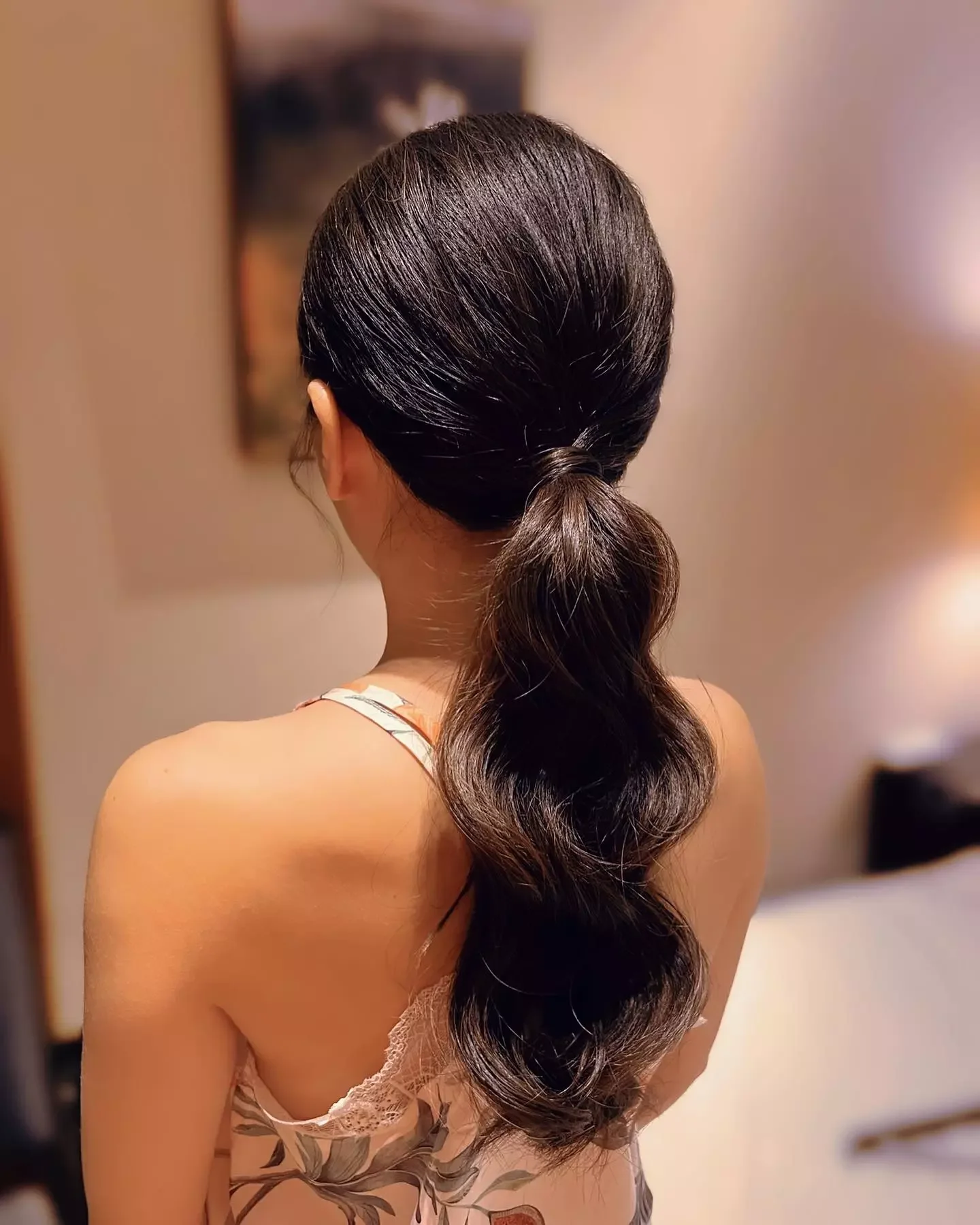 Back view of a sleek black low ponytail with soft waves through the tail