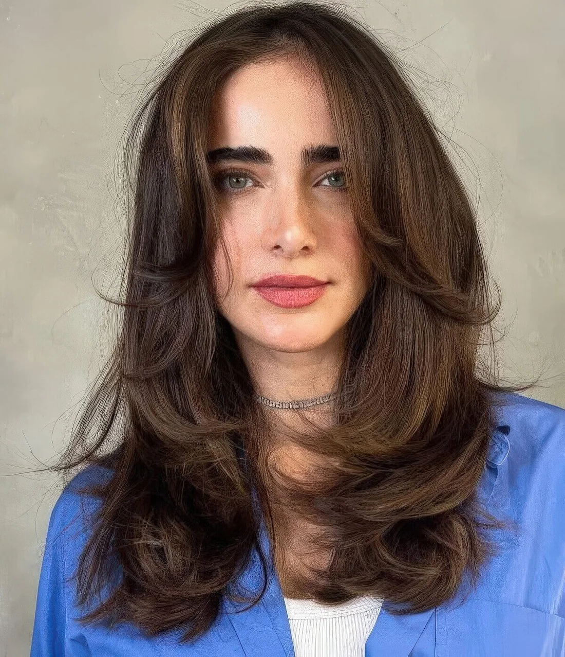 Dark brunette medium butterfly haircut with side bangs and curled ends plus a volume.