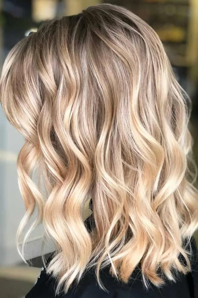 Back view of a shoulder-length blonde lob with broad waves and darker roots
