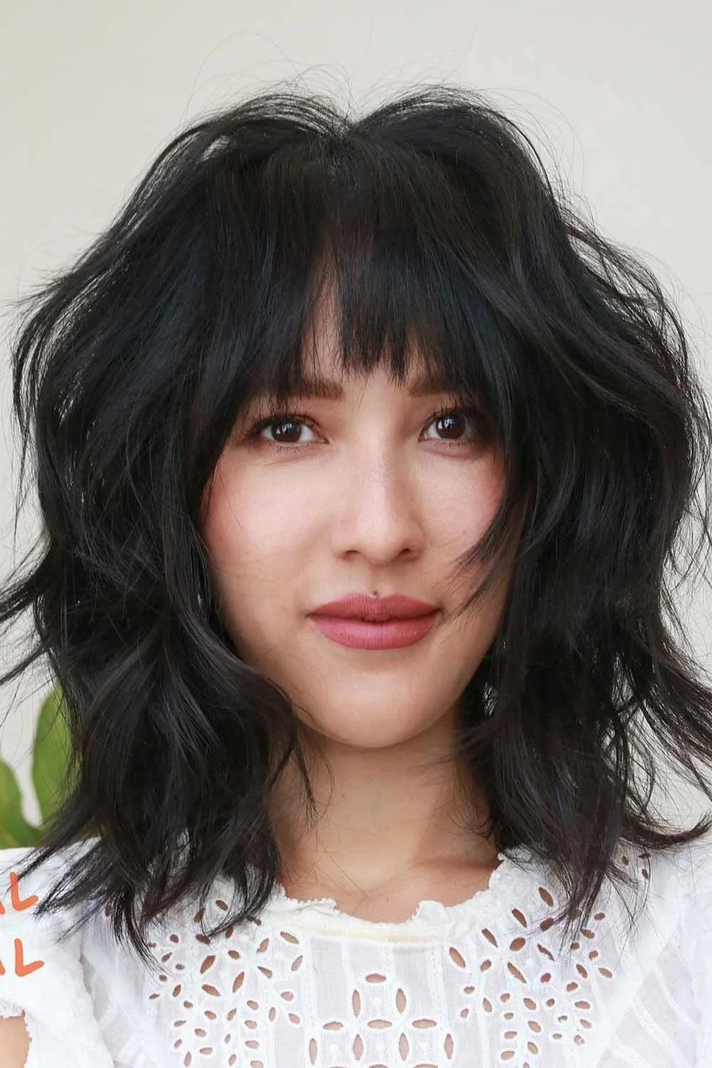 Front view of dark shoulder-length waves with a separated brow-length fringe