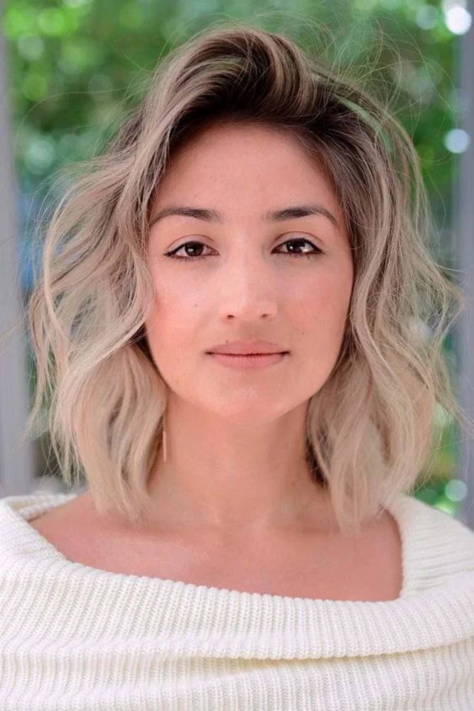 Front view of a shoulder-skimming blonde bob with relaxed waves and a lifted side opening