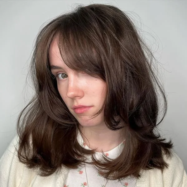 Dark medium shag haircut with curtain bangs and soft textured sides for thin fine hair