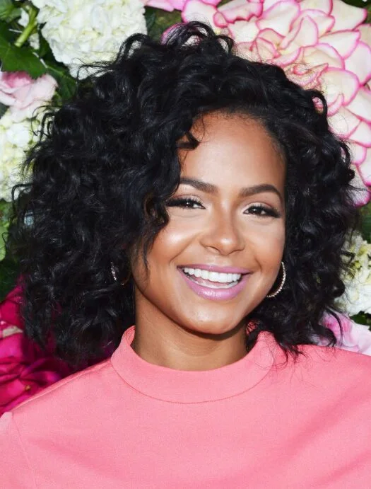 Black woman with a curly medium length haircut and rounded volume for thin fine hair inspiration