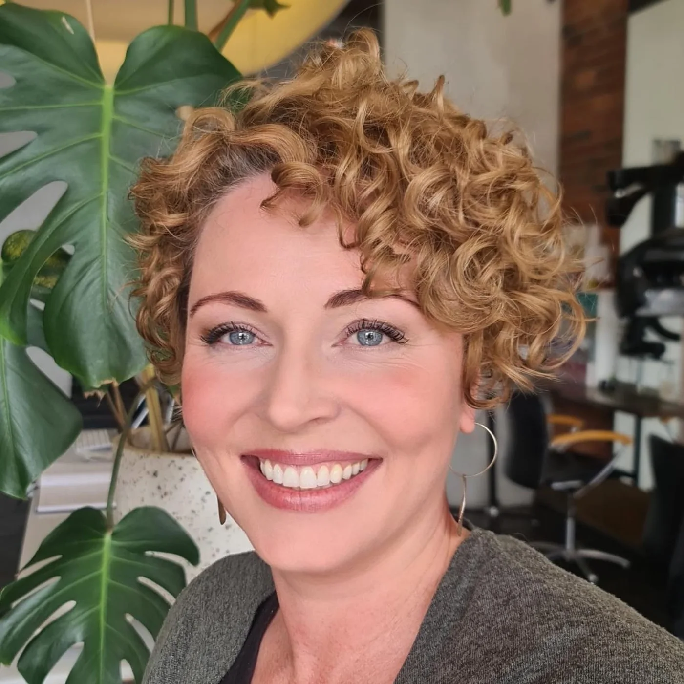 Bright curly medium length haircut with layered sides and full rounded volume for thin fine hair