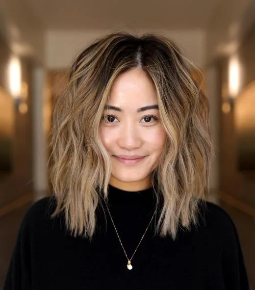 Rooted blonde medium shag haircut with curtain bangs and loose layers for thin fine hair