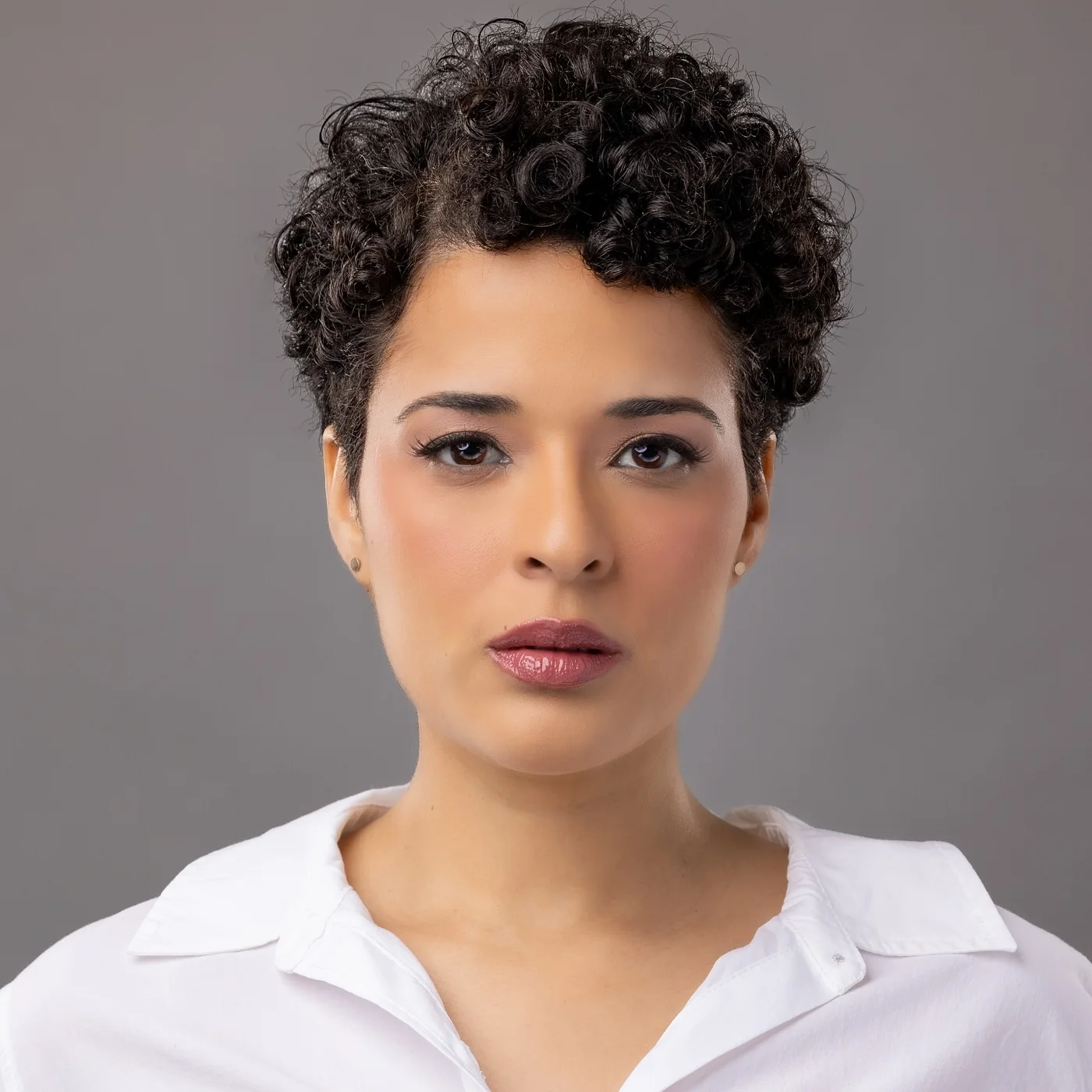 Short curly pixie cut with small curly bangs and tidy sides