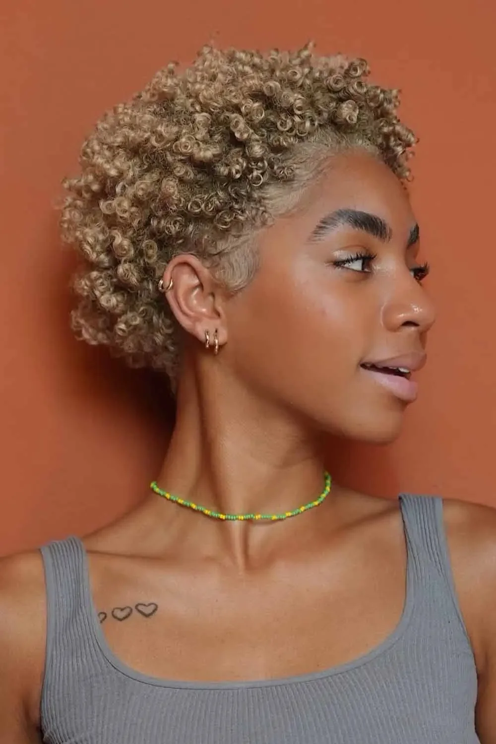 Blonde coily pixie cut with short side fringe and tapered sides