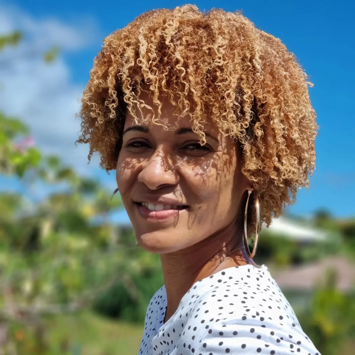 Golden curly pixie cut with soft bangs and short rounded shape