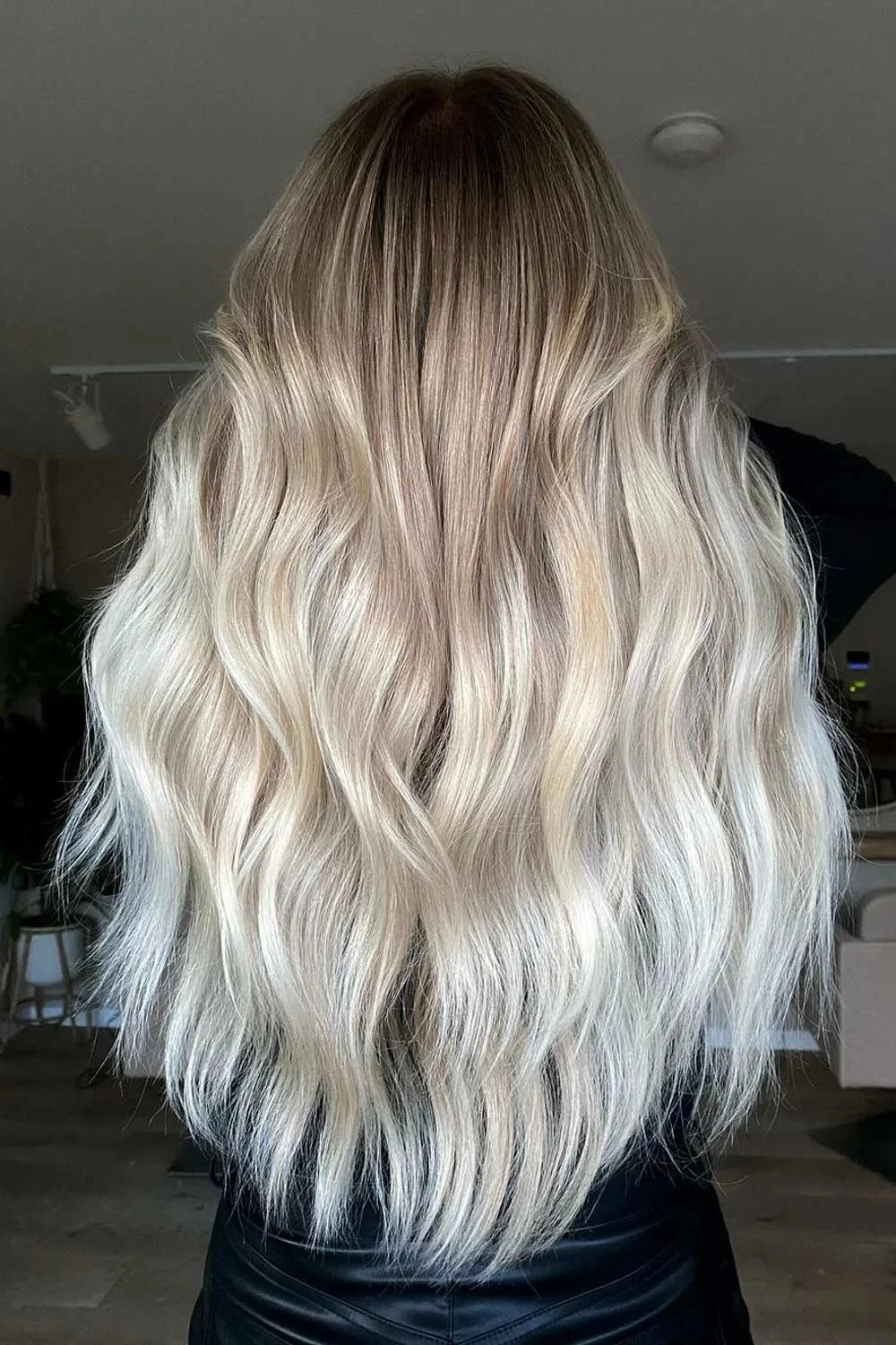 Back view of long pale blonde waves with a darker root area