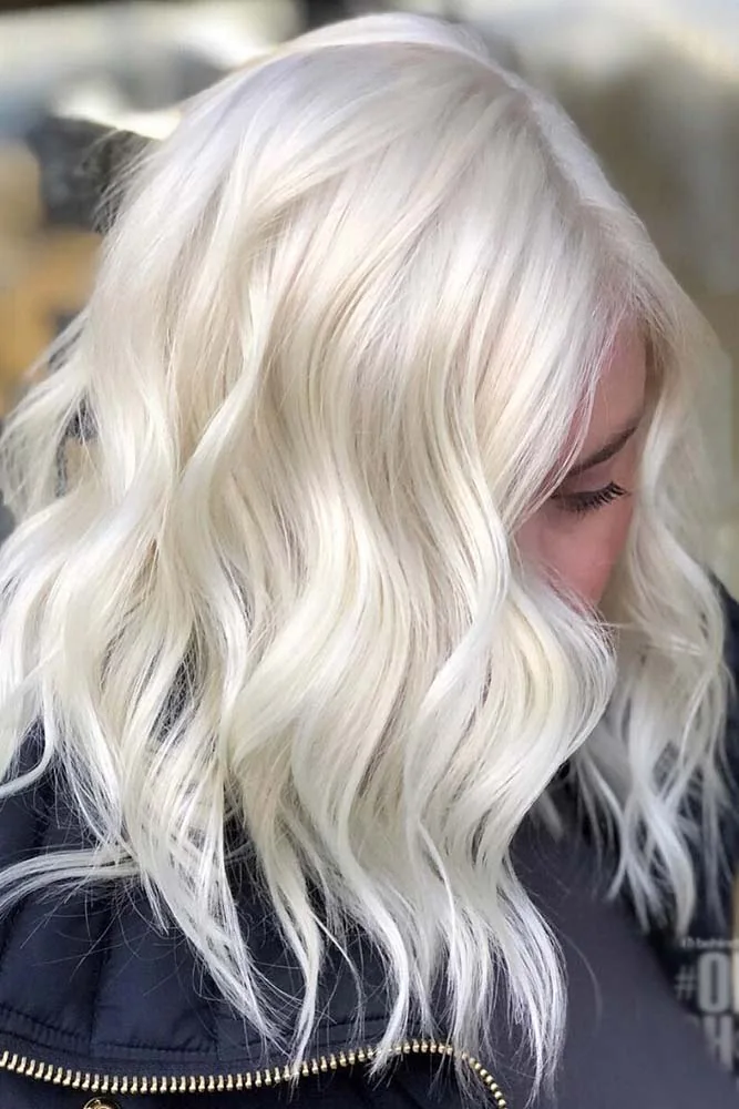 Side view of a creamy platinum wavy lob with a side opening