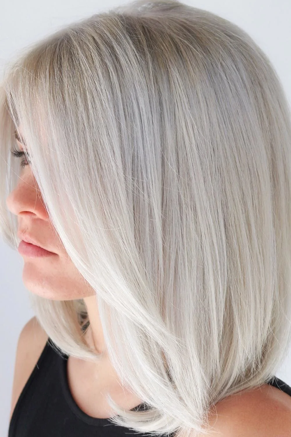 Close side view of a smooth white-blonde bob with a long front section