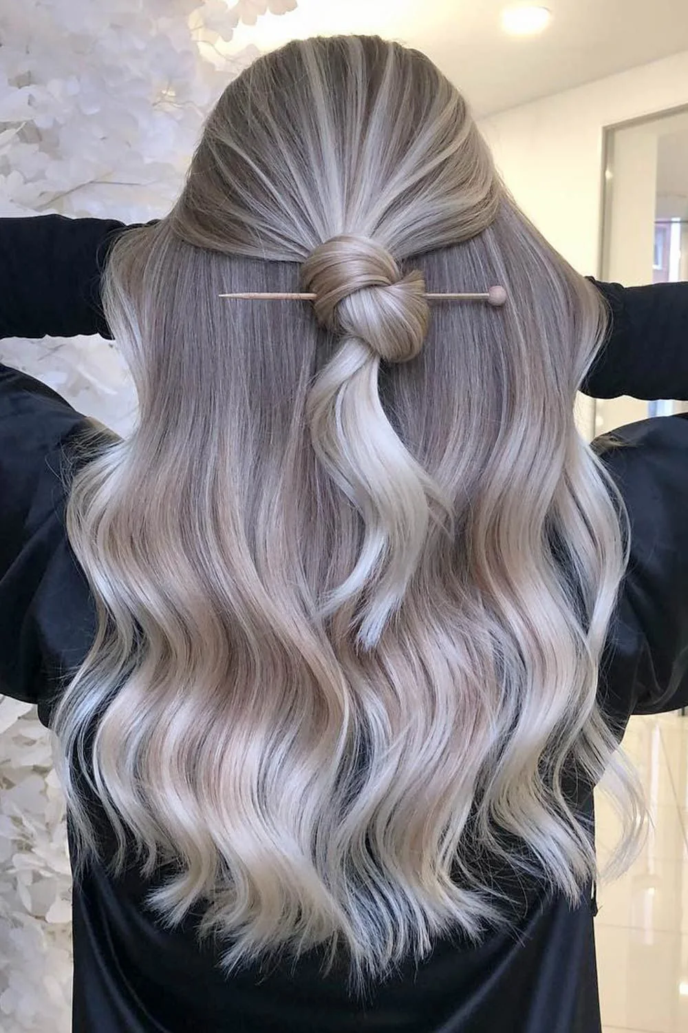 Back view of silver-blonde waves gathered into a small half-up knot