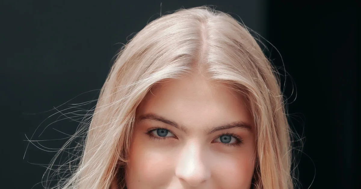 Blonde woman with long smooth straight hair against a dark background