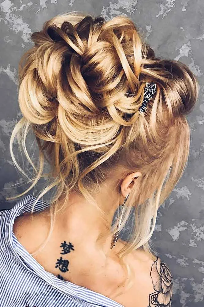 Golden hair arranged in a high looped bun with loose face-side strands