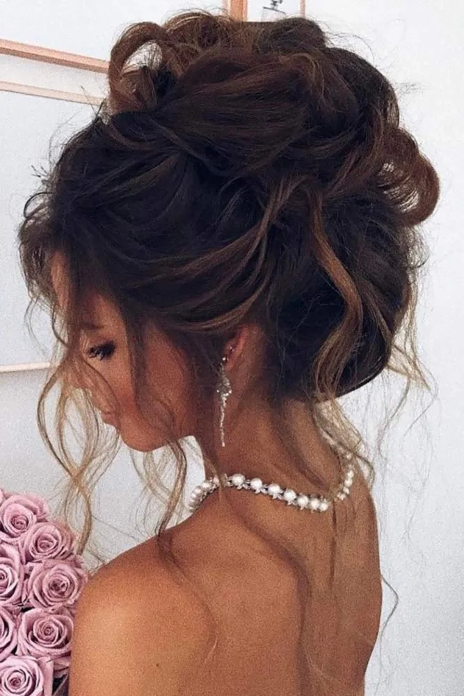 Dark hair in a loosely gathered high updo with curled tendrils beside the face