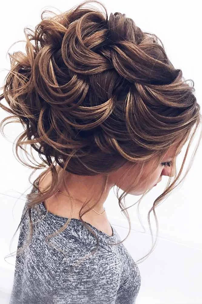 Highlighted brunette hair gathered into overlapping curled loops with loose neck strands