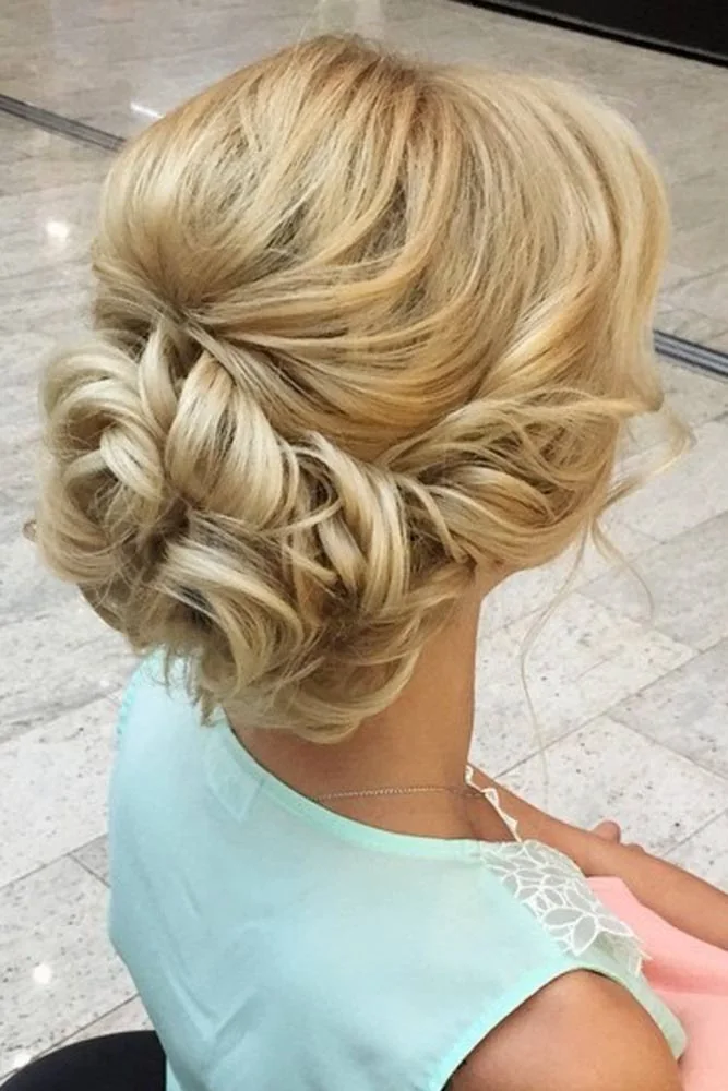 Golden blonde hair gathered into a low bun with interlaced sections across the back