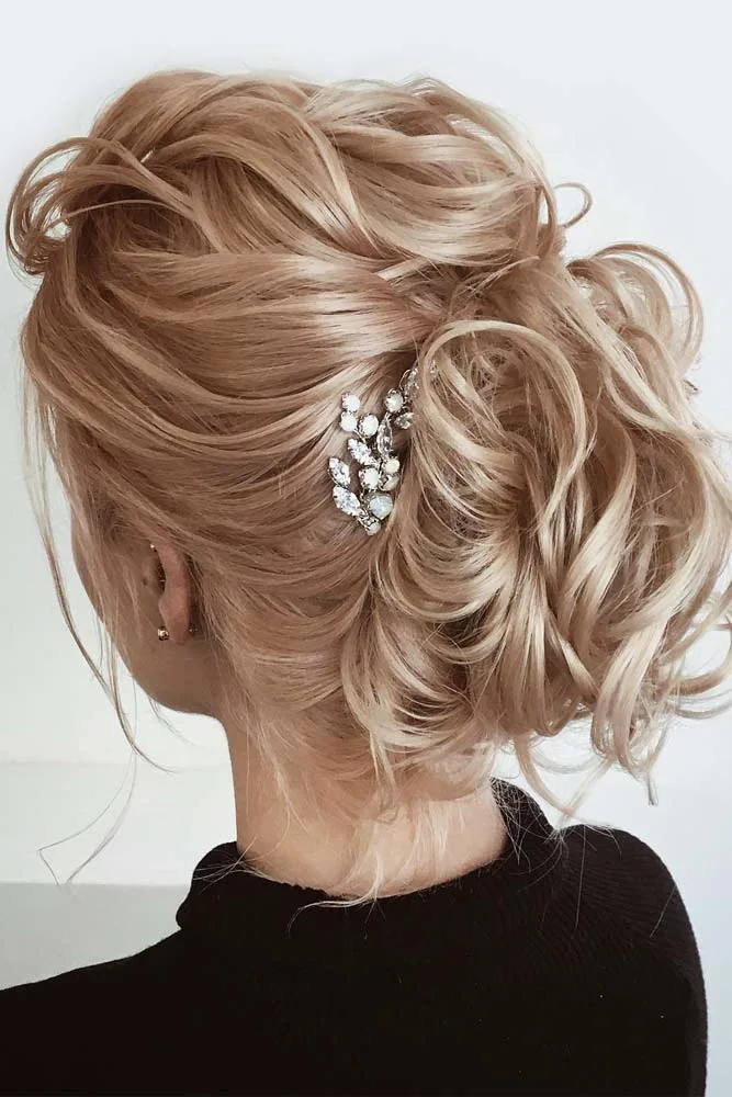 Rose-gold blonde hair in a rolled bun with a small sparkling side clip