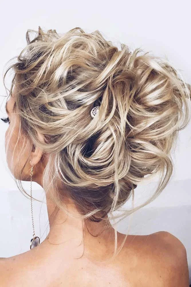 Highlighted blonde hair gathered into a wide updo of overlapping curls