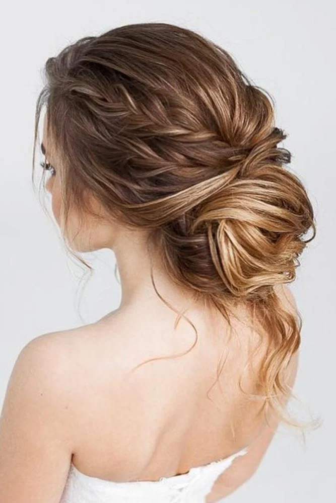 Brown hair with a side braid leading into a softly gathered low bun