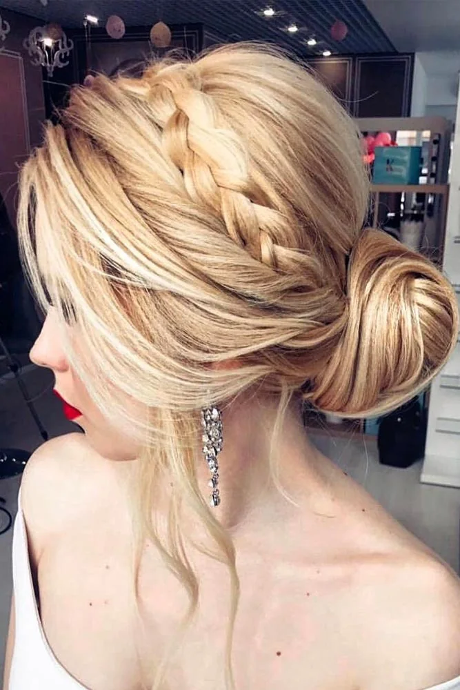 Blonde hair with a side braid joining a smooth low coiled bun