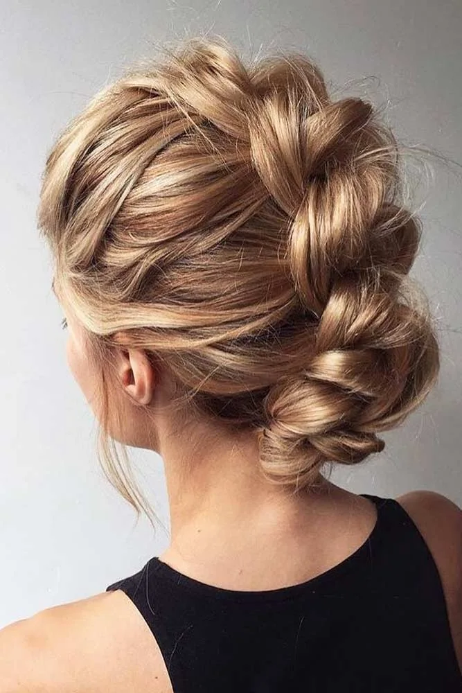 Blonde hair arranged in a broad braided back section tucked into a nape roll